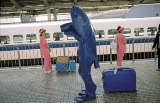 André Kuenzy, alias Blue Man, reiser verden rundt i sitt blå gummikostyme. Her er han på en jernbanestasjon i Japan. Videoene viser hvordan folk reagerer på et vesen så forskjellig fra dem selv. Foto: André Kuenzy 